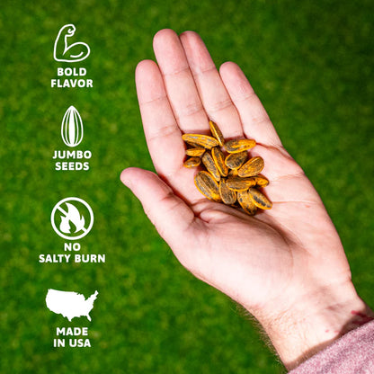 A hand holds Smackin' Sunflower Seeds - 1.5oz over green grass. To the left, icons say: Bold Flavors, Jumbo Seeds, No Salty Burn, and Made in USA with a USA map. Brand: Smackin' Sunflower Seeds.