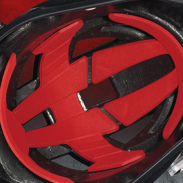 Close-up view of the inside of a bicycle helmet, showing black protective foam and bright red padded inserts arranged for cushioning and support.