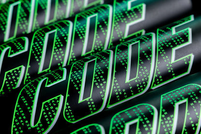 Close-up of the word CODE in bold, green letters with a digital matrix-style effect, mirroring the precision of the Marucci 2025 Code (-3) BBCOR Baseball Bat (MCBCD). Small green digits fill each letter on a sleek black background.