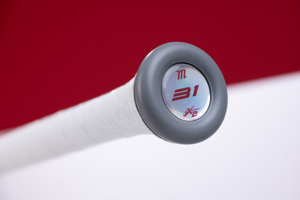 Close-up of a Marucci CATX2 Connect (-8) USA Baseball Bat handle with white grip tape and anti-vibration tech. The knob end cap shows 31 and 1/2 in red on silver, set against a bold red and white background.