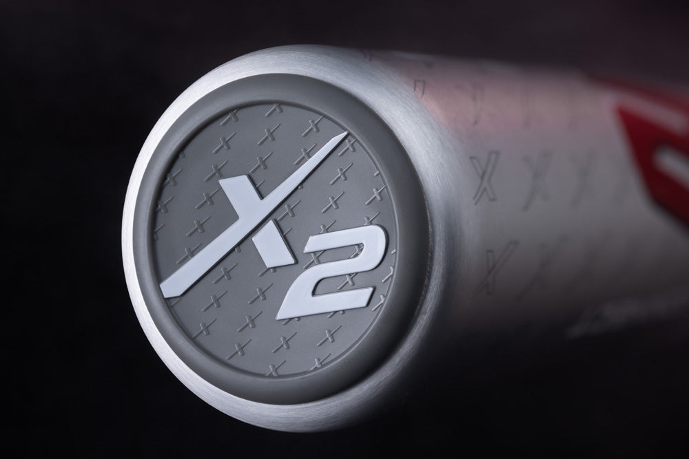 Close-up of the 2025 Marucci CATX2 Connect (-3) BBCOR Baseball Bat (MCBCCX2) end cap, showcasing a silver-gray finish with raised white X2 text, small Xs pattern, and advanced anti-vibration tech by Marucci.