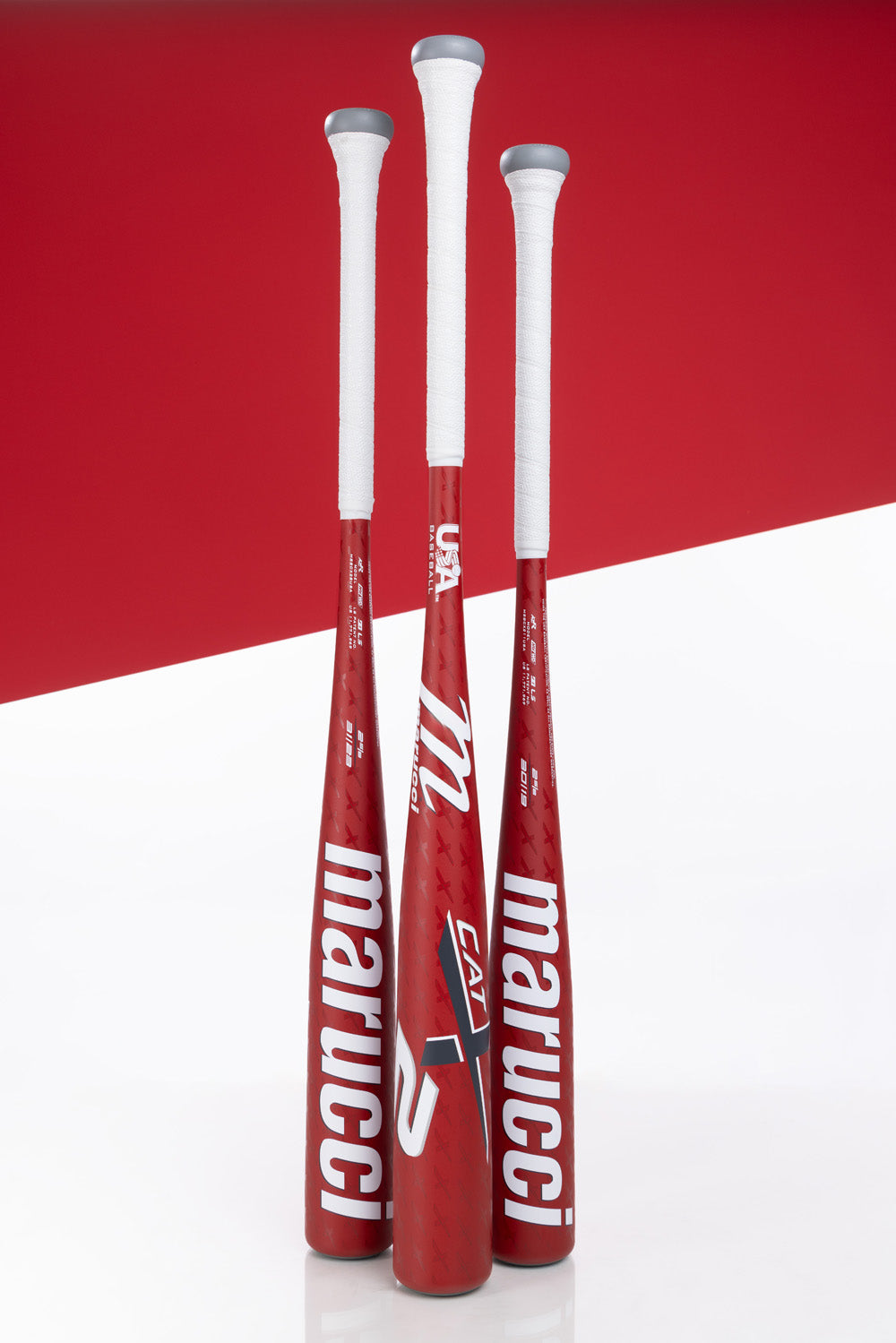 Three Marucci CATX2 (-5) 2 5/8" USA Baseball Bats (MSBCX25USA) with white grips stand upright against a white and red background, showcasing sleek design and bold Marucci branding for a standout look.