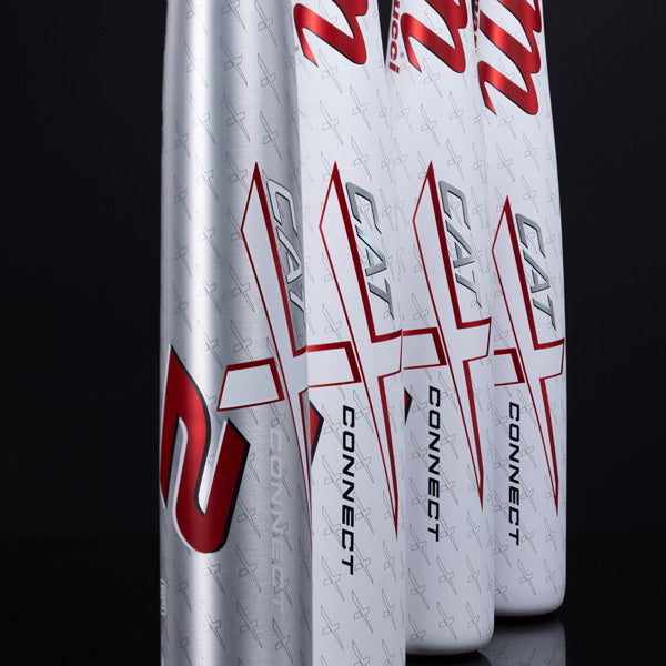 Three silver CAT X Connect baseball bats stand upright in a row, featuring bold red and black graphics and the number 2 on the closest bat, against a black background.
