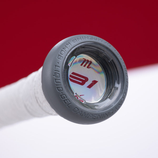 Close-up of the end cap of a tennis racquet handle, featuring the text 31 and a symbol inside a clear, circular window; the handle is wrapped in white grip tape with a red background.