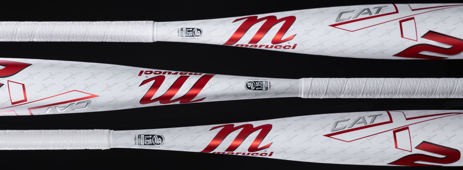 Three Marucci CATX baseball bats are shown horizontally against a black background, featuring white bodies, red m logos, and silver and red lettering with subtle crossed bats pattern in the background.