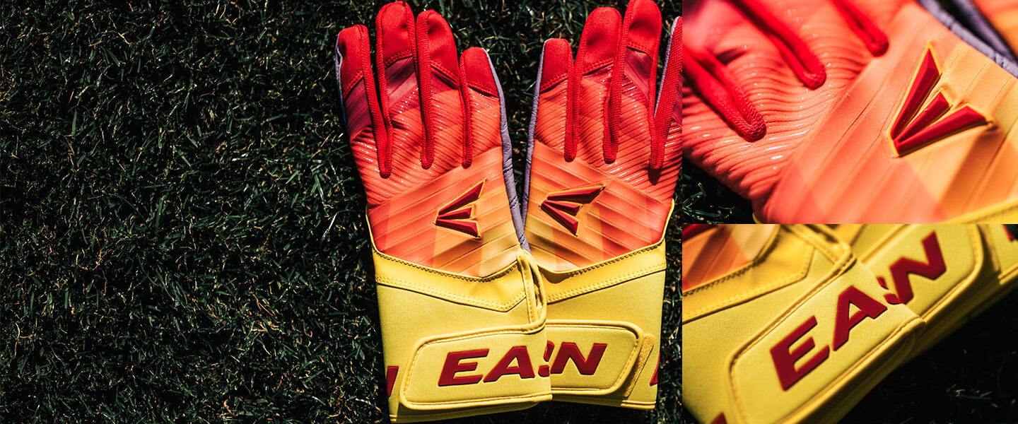 A pair of yellow and red goalkeeper gloves with the brand name EAN and a stylized logo, lying on green grass. A close-up inset highlights the brand name on the glove.