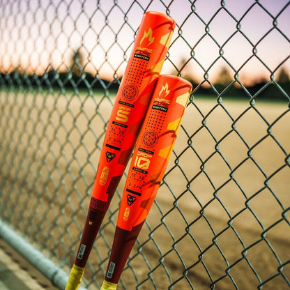 Two baseball bats, including the 2025 Easton Hype Fire JBB (-10) 2 3/4" USSSA Baseball Bat by Easton, lean against a fence.
