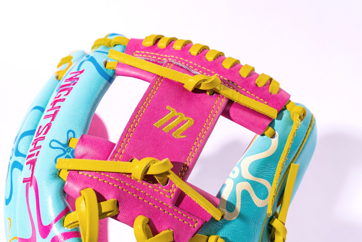 A close-up of the Marucci NightShift Robert Sponge 11.75" Baseball Glove, crafted from Japanese-tanned steerhide, with “NIGHT SHIFT” text, a stylized M on pink leather, abstract patterns, and yellow lacing by Marucci.