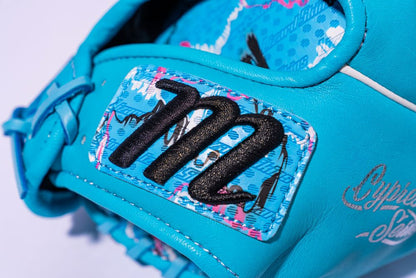 Close-up of the Marucci NightShift Blue Lizard 11.5" Baseball Glove, crafted from Japanese-tanned steerhide leather and featuring a bold black “M” logo on a patterned patch with pink and white details, fine stitching, and part of a gold script logo.