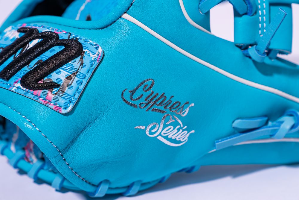 Close-up of a vibrant blue Marucci NightShift Blue Lizard 11.5" Baseball Glove, crafted from Japanese-tanned steerhide and featuring "Cypress Series" on the leather plus a patch with a black stitched M on a multicolored background.