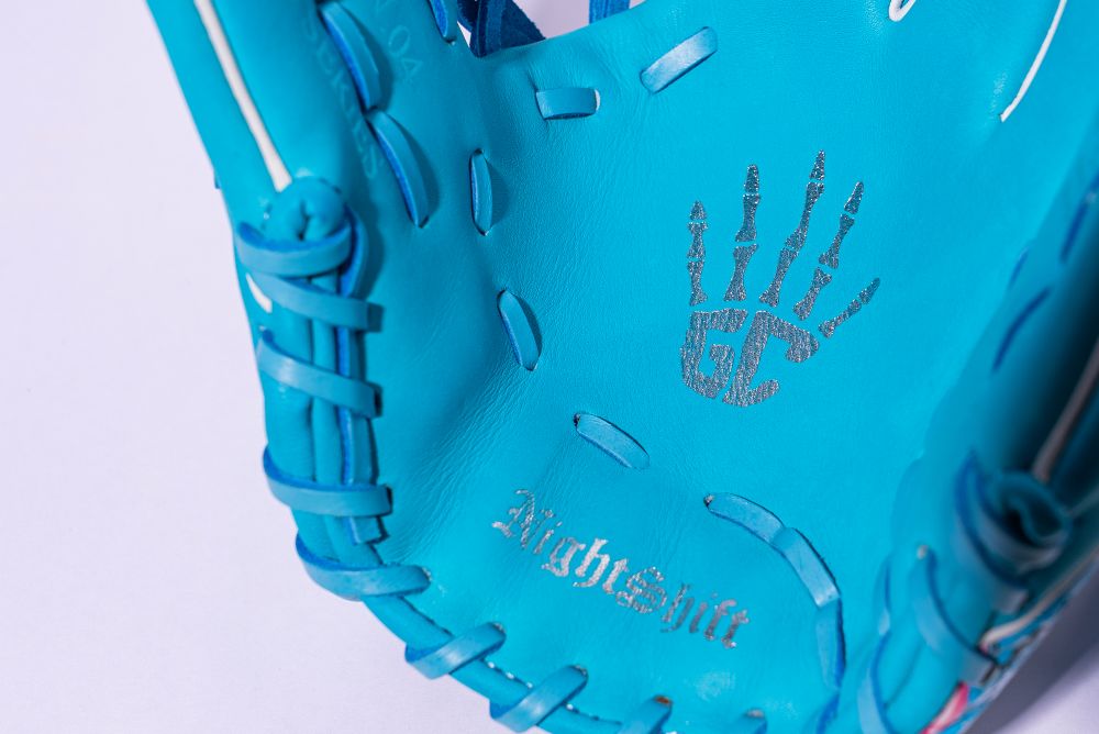 Close-up of a Marucci NightShift Blue Lizard 11.5" Baseball Glove (MFGNTSHFT-0405), showing stitched "AlrightShit" text and a handprint with "GC," crafted from premium Japanese-tanned steerhide leather.