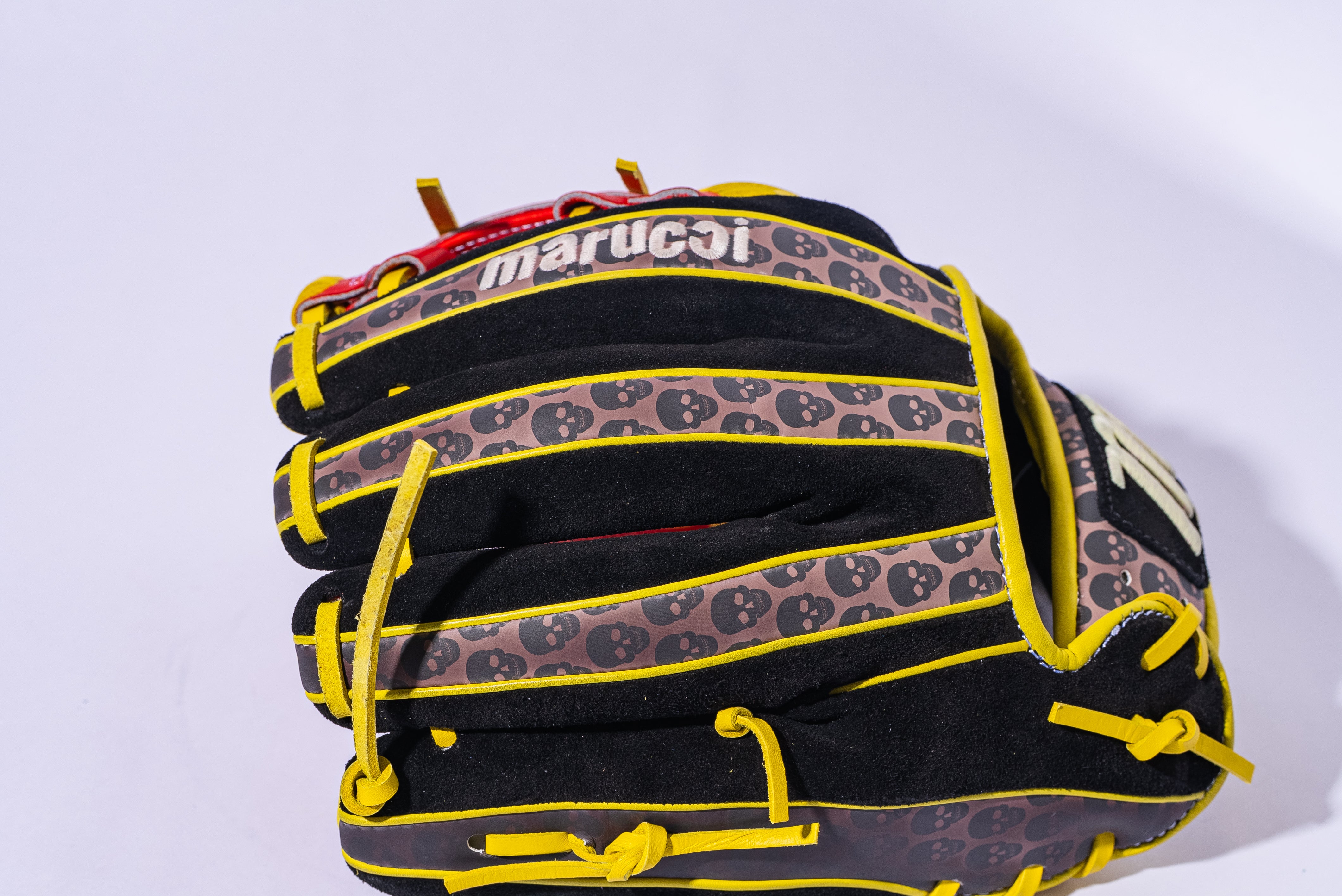 The Marucci NightShift Hot Head 11.5" Baseball Glove (MFGNTSHFT-0406) features a black and yellow design with small black skulls on the fingers and is made from Japanese-tanned steerhide leather, shown against a white background.