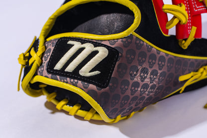 A close-up of the Marucci NightShift Hot Head 11.5" Baseball Glove (MFGNTSHFT-0406) in black and yellow Japanese-tanned steerhide, with a white stitched M patch and a gray section featuring a repeated skull pattern.
