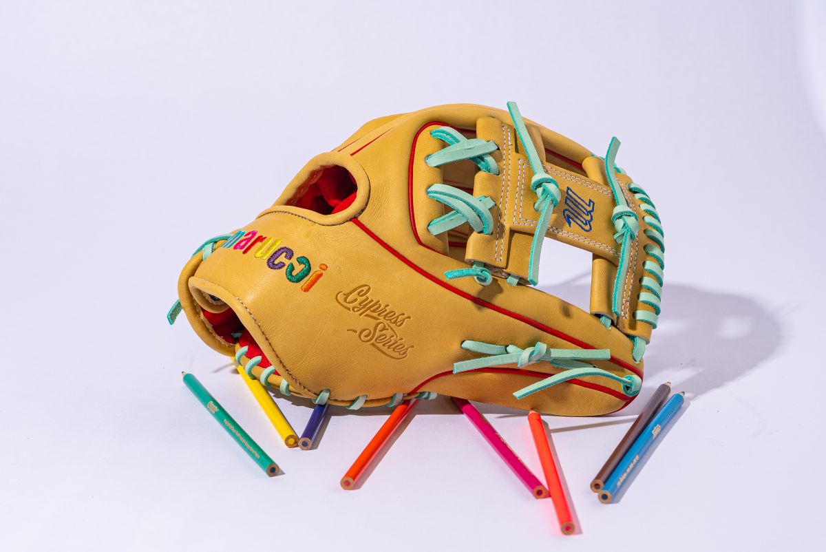 The Marucci NightShift Coloring Book 11.5" Baseball Glove (MFGNTSHFT-0404) features Japanese-tanned steerhide, colorful laces, and embroidered text, shown with scattered colored pencils on a white background.