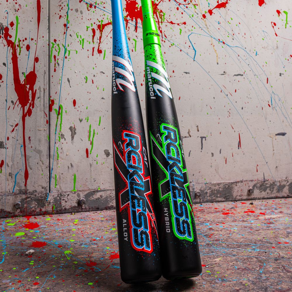 Two Marucci 2026 CAT X RCKLESS (-3) BBCOR Baseball Bats stand upright against a wall splattered with red, blue, and green paint. Paint covers the floor as well, adding vibrant energy to the scene.