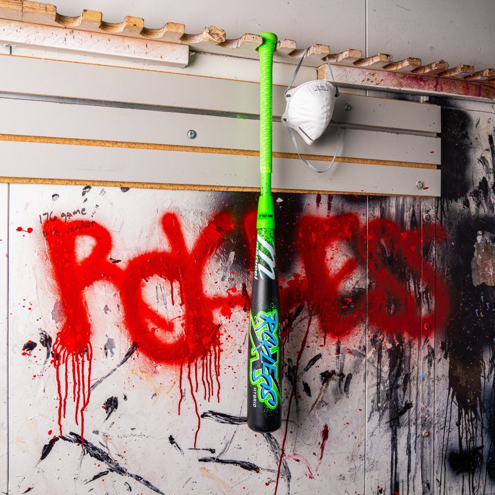 A Marucci 2026 CAT X RCKLESS Hybrid (-5) USSSA Baseball Bat (MSBCRH5 DEMO) in green and black hangs on a paint-splattered wall beside a white mask, with "PROGRESS" spray-painted in red graffiti behind it.