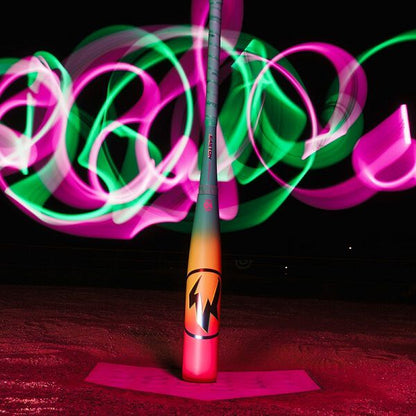 The 2026 Easton Hype Fire (-11) 2 5/8" USA Baseball Bat (EUS6HYP11) stands upright on home plate at night, illuminated by swirling pink and green light trails against a dark background.