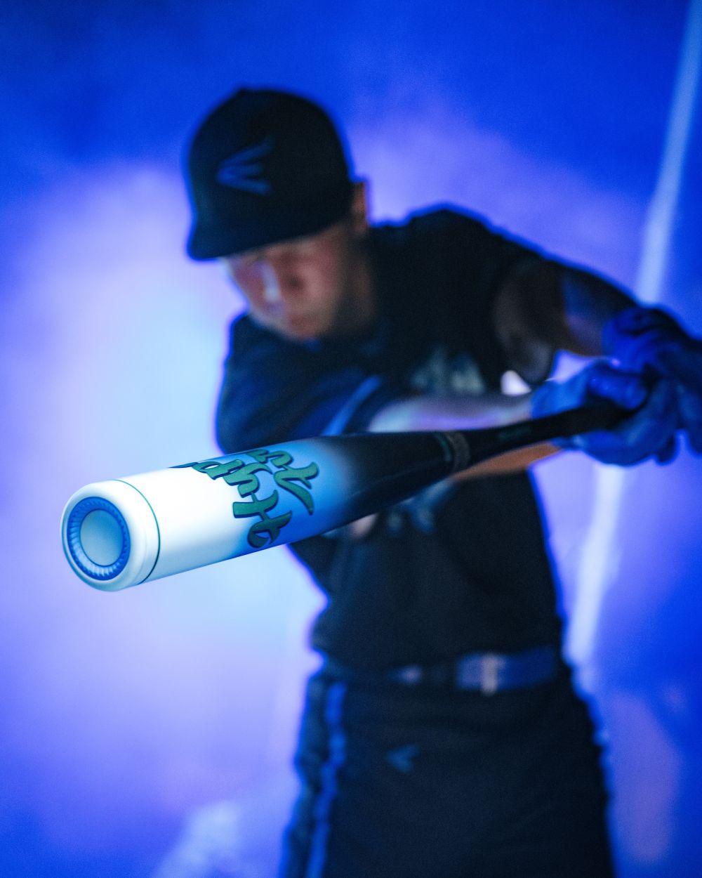A baseball player swings the 2027 Easton Hype Fire (-3) BBCOR Baseball Bat (EBB7HYP3) toward the camera, highlighting the TCT Barrel in sharp focus while the player is blurred in the background, all set against dramatic blue lighting and swirling mist.
