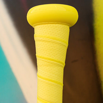Close-up of the bright yellow textured grip and knob of a Rawlings 2026 Clout AI (-3) BBCOR Baseball Bat (RBB6C3), set against a blurred, multicolored background.