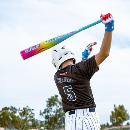 A baseball player in a white helmet, black jersey with number 5, and striped pants readies to swing the 2026 Easton Hype Fire (-5) USSSA Baseball Bat by Easton. Trees and a blue sky provide the backdrop.