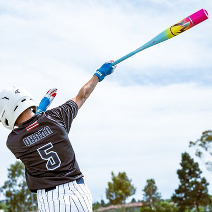 A baseball player in a black OHANA jersey with number 5 swings the 2026 Easton Hype Fire (-5) 2 3/4" USSSA Baseball Bat (EUT6HYP5) by Easton outdoors under a blue sky, with trees visible in the background.