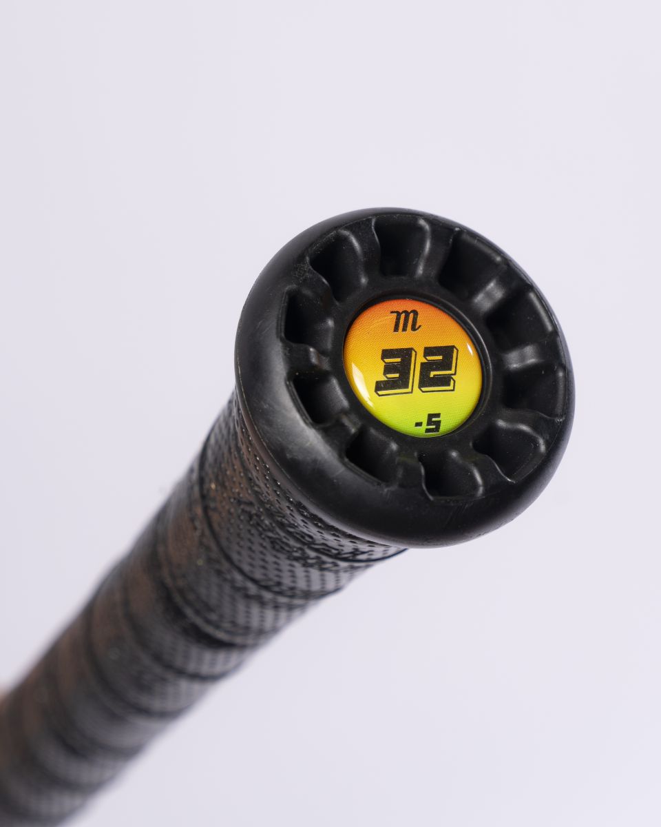 Close-up of the end cap of a black Marucci 2027 RCKLESS Gen 2 (-5) 2 3/4″ USSSA Baseball Bat (model MSBR25), featuring a yellow and orange label with “32” and “-5” printed on it. The handle is wrapped with textured black grip tape.