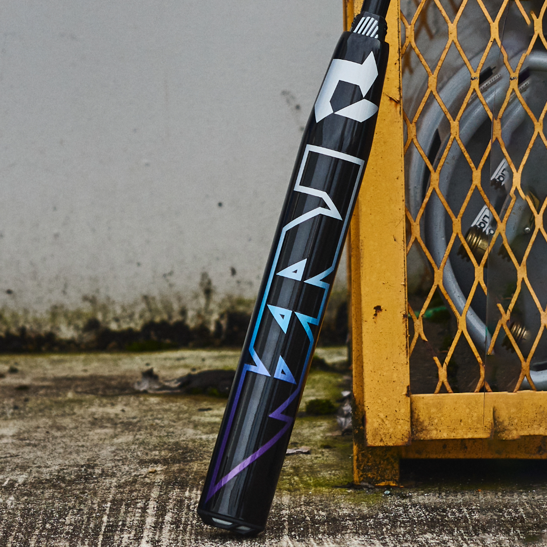 A 2026 DeMarini Prism+ (-11) Fastpitch Softball Bat (WBD2636010) with a Continuous Fiber Composite Barrel leans against a fence.