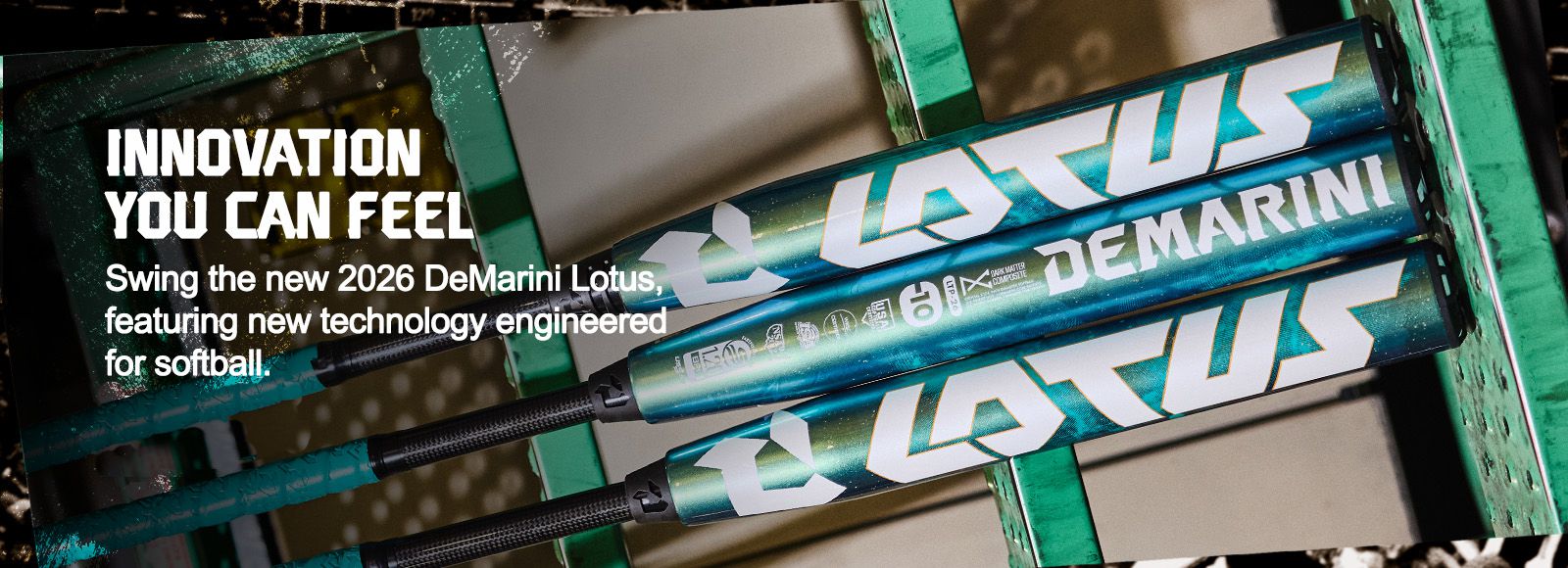 Two teal and white DeMarini Lotus softball bats rest on a green metal rack, with bold text promoting the innovative 2026 DeMarini Lotus bat and its new technology for softball players.