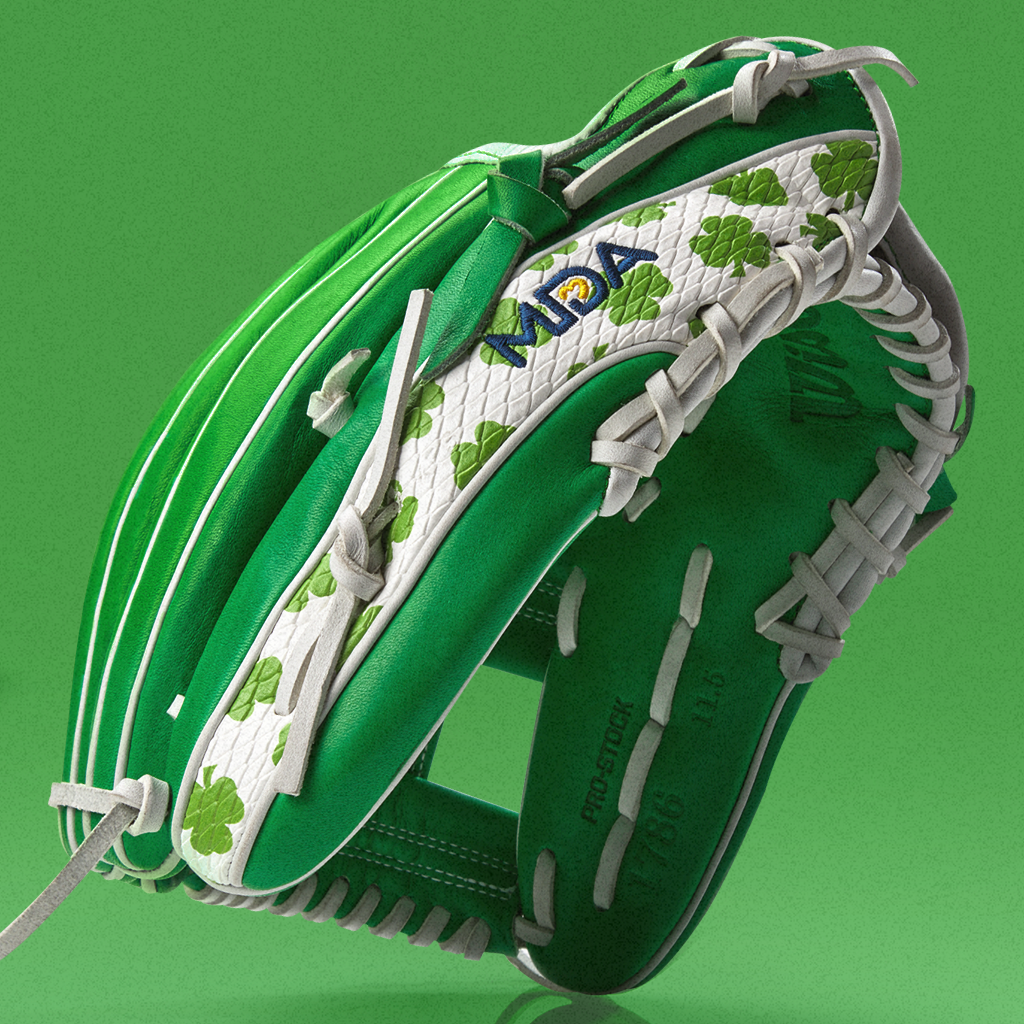 A green and white baseball glove decorated with green four-leaf clovers and white laces, displayed against a solid green background.