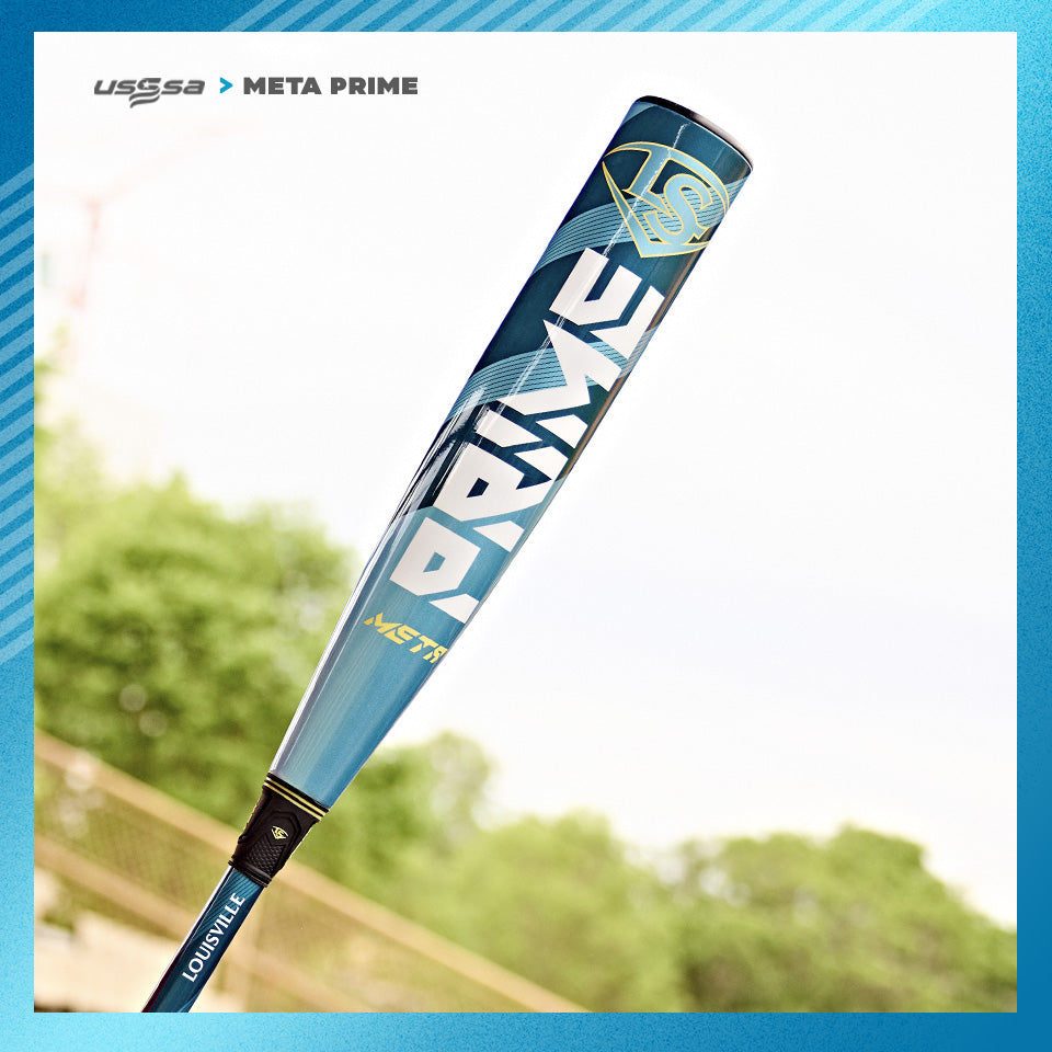 A close-up of the 2025 Louisville Slugger Meta Prime (-8) USSSA Baseball Bat (WBL2971010 demo), blue and silver, stands upright outdoors with trees and a blurred fence in the background. Bold PRIME lettering is visible on the bat.