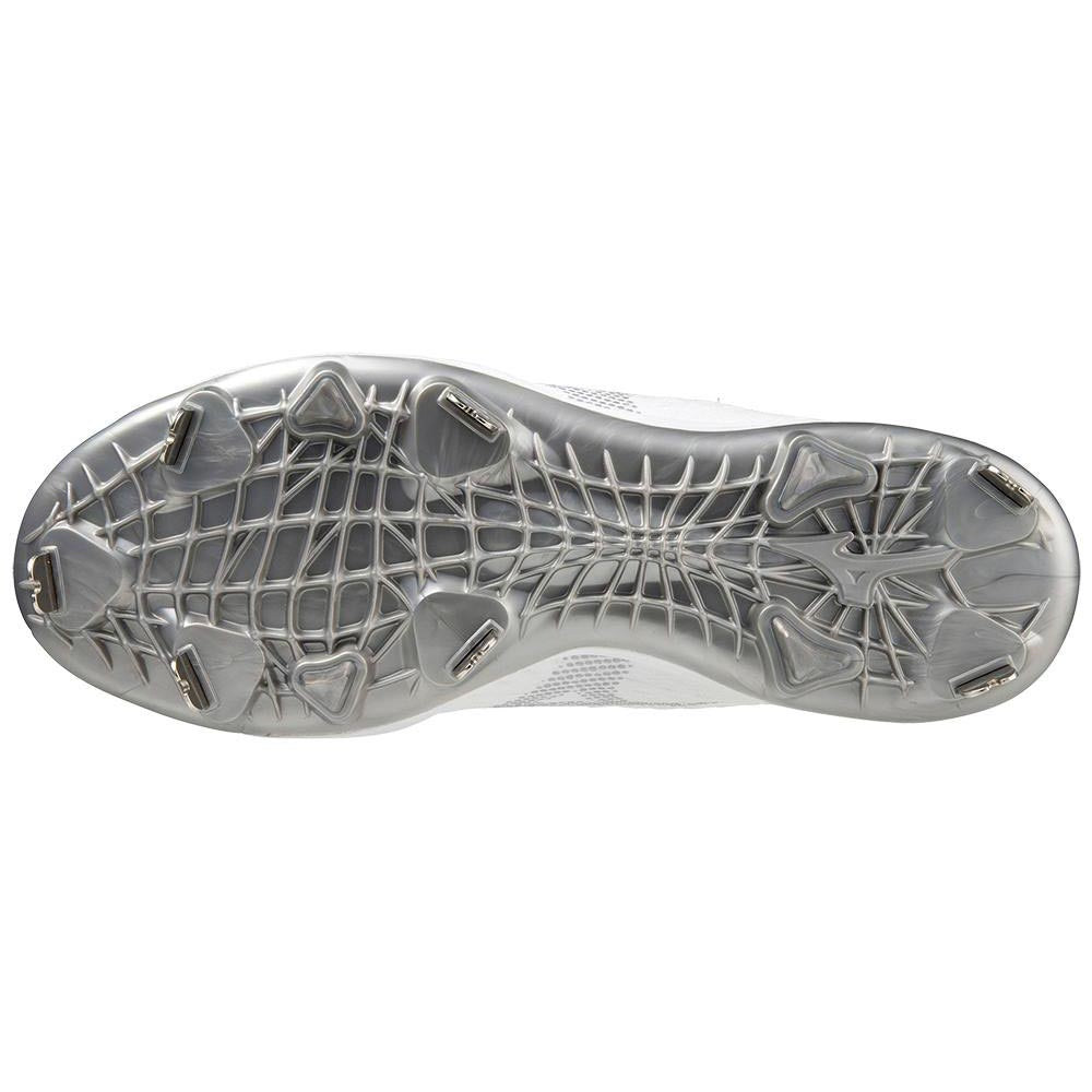 The image shows the bottom view of a silver and white Mizuno Dominant 4 Men's Metal Baseball Cleat (320667) featuring a web-like tread and seven metal studs.