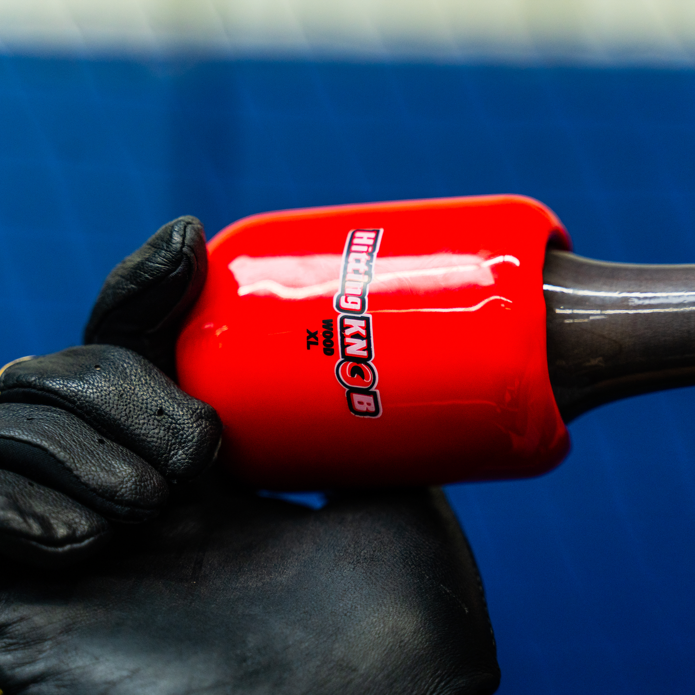 A hand holding The Hitting Knob Bat Weight by Hitting Knob, a baseball training aid designed to help improve bat speed.