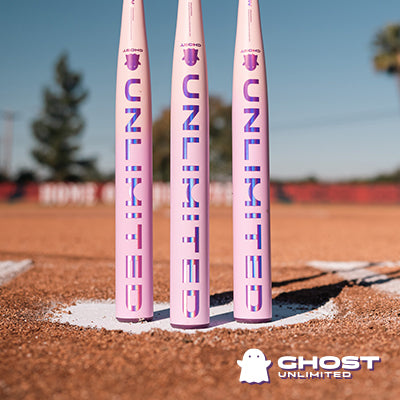 Three pink 2026 Easton Ghost Unlimited (-10) Fastpitch Softball Bats stand upright on a dirt field, each featuring UNLIMITED in purple. The white ghost logo and Easton Ghost Unlimited branding appear in the bottom right corner.