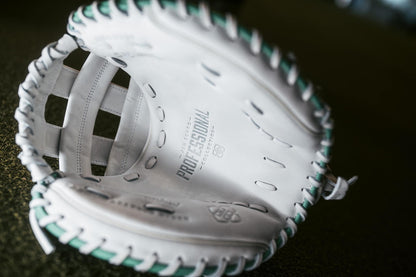 A close-up of the Easton Jen Schro "The Rudi" 34" Fastpitch Catcher's Mitt (RUDI-2024), crafted from premium USA steerhide leather in white with green stitching, shows the palm area embossed with "Professional Collection.