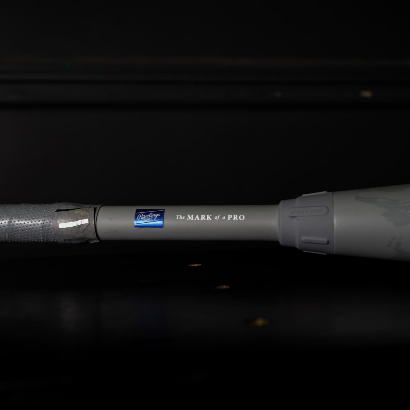 A close-up of the 2025 Rawlings Mantra Reverse (-10) Fastpitch Softball Bat handle shows The MARK of a PRO and blue Rawlings logo, highlighting the iconic style and design of this elite Rawlings bat against a dark backdrop.