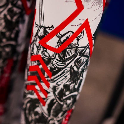 Close-up of a surface with intricate black and white medieval knight designs and bold red geometric lines—reflecting the dynamic style of the DeMarini 2026 Exile (-3) BBCOR Baseball Bat: WBD2589010.