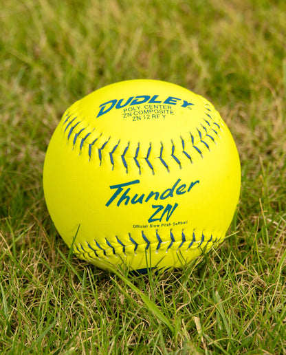 A Dudley USSSA Thunder ZN Classic M 12" 40/325 Composite Slowpitch Softball (4U540Y) with bright yellow cover and blue lettering rests on green grass, ideal for competitive slowpitch games.