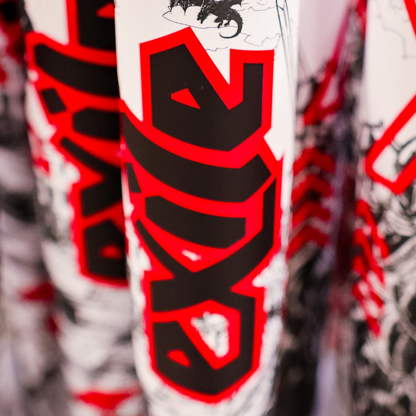 Close-up of the bold black and red 2026 DeMarini Exile (-3) BBCOR Baseball Bat: WBD2589010 graphic on white, featuring abstract patterns that highlight its one-piece alloy design by DeMarini.