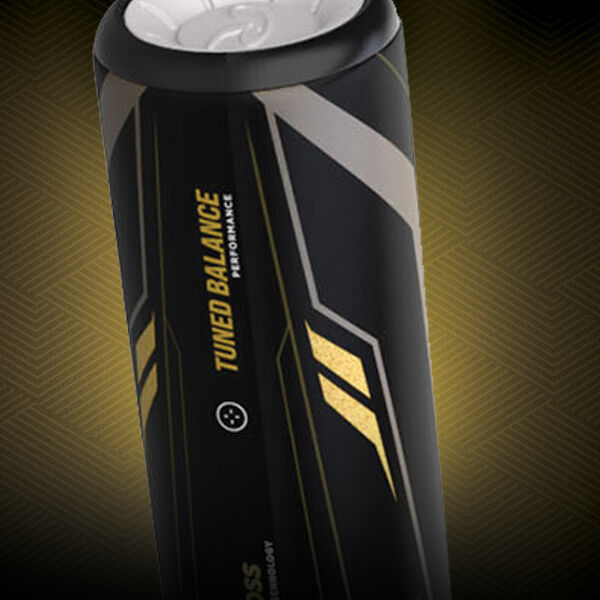A close-up of a sleek black can with gold and silver geometric accents, featuring the text TUNED BALANCE PERFORMANCE on its side, set against a textured, patterned background.