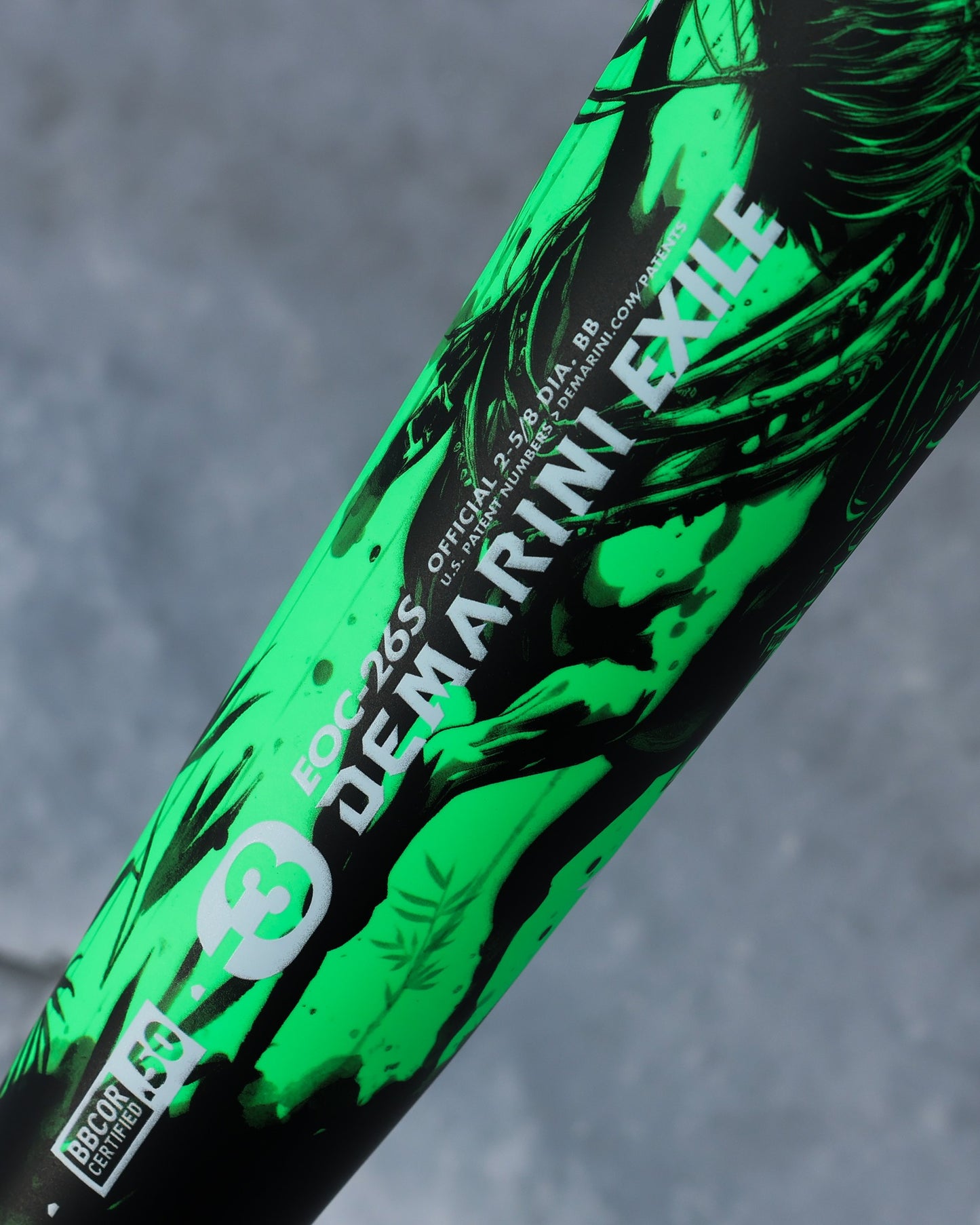 Close-up of the 2026 DeMarini Exile Samurai (-3) BBCOR Baseball Bat: WBD2652010, featuring branding and certification logos on its X14 Alloy Barrel against a blurred gray background.