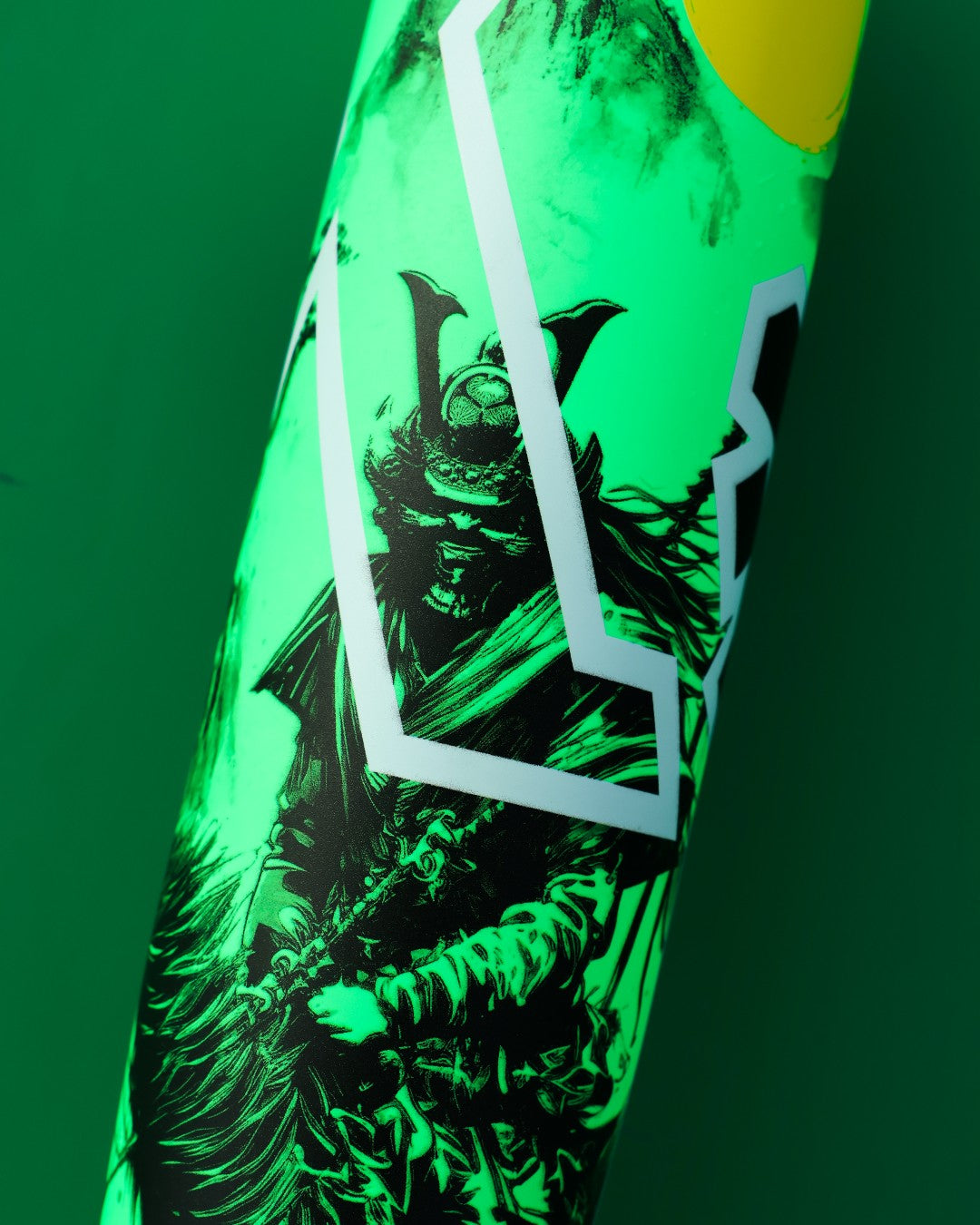 A close-up of the 2026 DeMarini Exile Samurai (-3) BBCOR Baseball Bat (WBD2652010), in green and yellow, features a samurai warrior illustration with white geometric lines, and is crafted with an X14 Alloy Barrel for high school and college play.