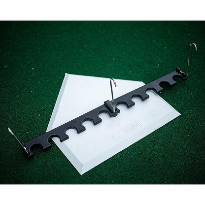 The Rawlings Portable Fence Bat Rack (BATRACK), a black plastic holder with eight slots and two metal hooks, sits on a green surface over a clear plastic sheet, resembling a compact dugout organizer.