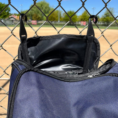 The Champro Sports Champro Boss Wheeled Catcher's Bag: E92 with a spacious bat pocket hangs on a chain link fence.