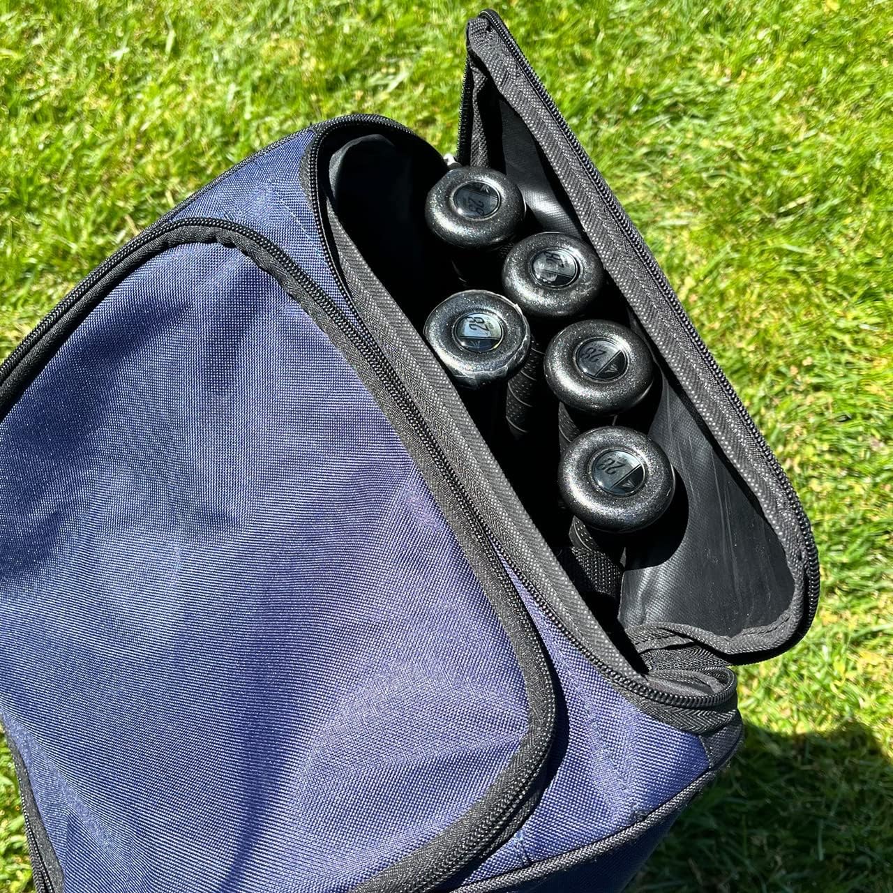 A partially open Champro Sports Champro Boss Wheeled Catcher's Bag: E92 sits on grass, showing the handles of several baseball or softball bats inside.