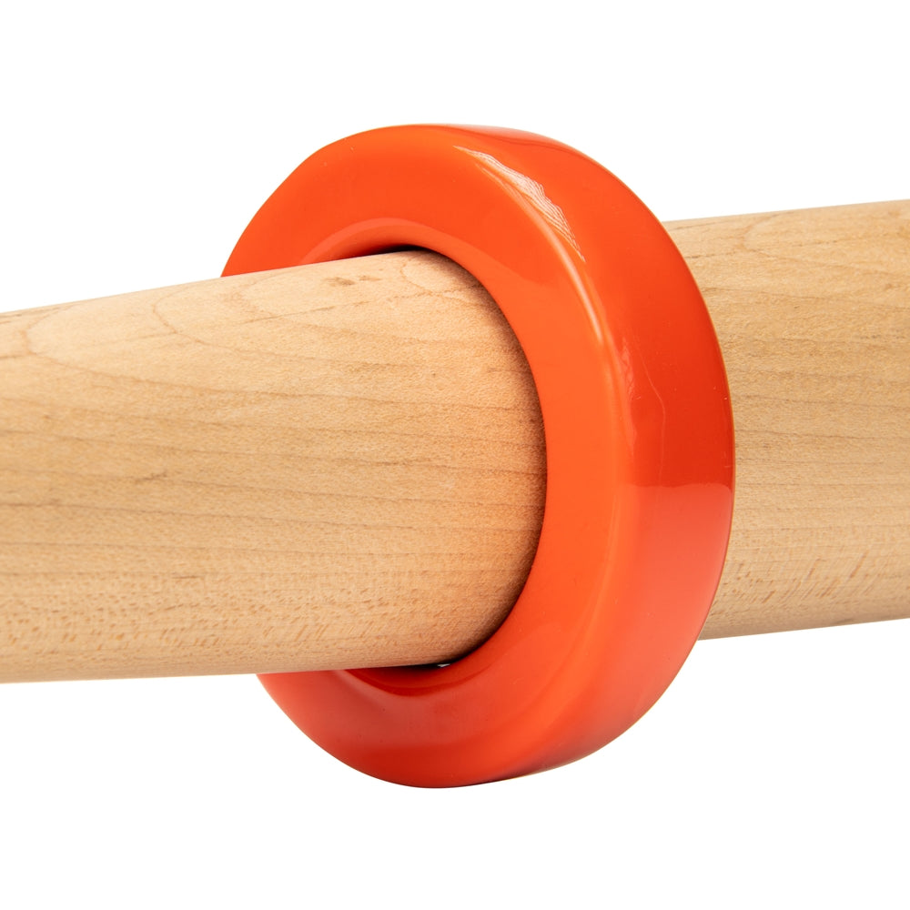 A Champro Sports Bat Weight (A014-A019), a glossy orange ring, is placed around a smooth, light wooden training bat against a white background.