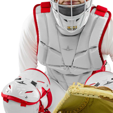 A baseball catcher wearing a gray chest protector, shin guards, and helmet with red accents, holding a tan glove, ready in a crouched position.