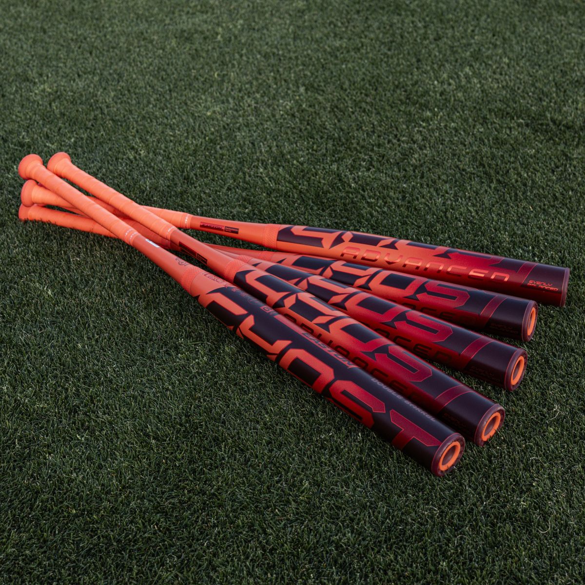Four Easton Ghost Advanced (-8) fastpitch softball bats are arranged on green turf, handles aligned and barrels fanned out, showcasing the Easton branding and featuring Double Barrel construction for top performance.