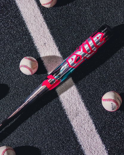 A 2026 DeMarini Exile Cyborg (-3) BBCOR Baseball Bat (WBD2654010) with bold red and white EXILE text lies on a striped blacktop, surrounded by four baseballs.