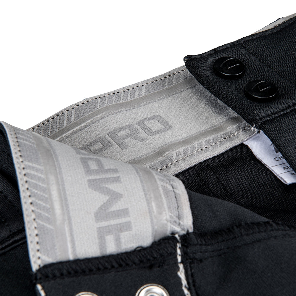 Close-up of the waistband and closure of Champro Sports Youth Triple Crown 2.0 Tapered Baseball Pants (BP64Y) in black, showing gray and white interior branding, metal grommets, and two black buttons.