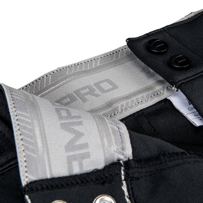 Close-up of the waistband and closure of Champro Sports Youth Triple Crown 2.0 Tapered Baseball Pants (BP64Y) in black, showing gray and white interior branding, metal grommets, and two black buttons.